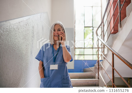 Tired nurse taking break during hospital shift, calling with family. 131655276