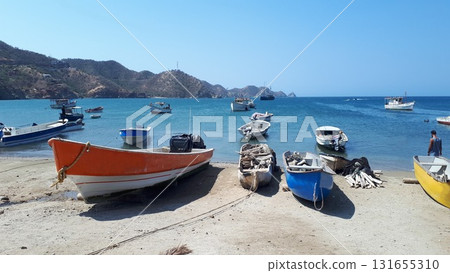 Colorful fishing boats rest on a sandy shore beside calm turquoise waters 131655310