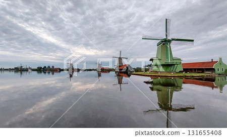 Traditional Dutch windmills reflect in the calm water 131655408