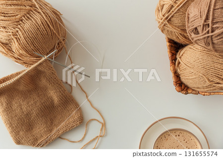 Knitting Project with Cup of Cappuccino on White Table in Cozy Setting Knitting Project with Cup of Cappuccino on White Table in Cozy Setting 131655574