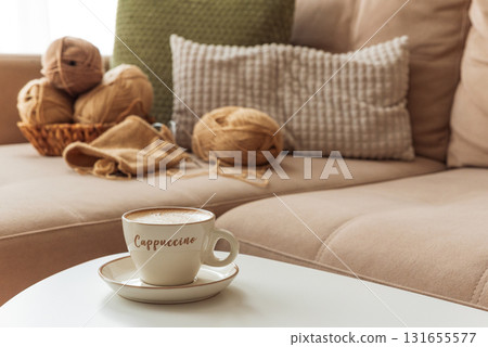 Cozy Living Room with Yarn, Pillows and Cup of Cappuccino on White Table Cozy Living Room with Yarn, Pillows and Cup of Cappuccino on White Table 131655577