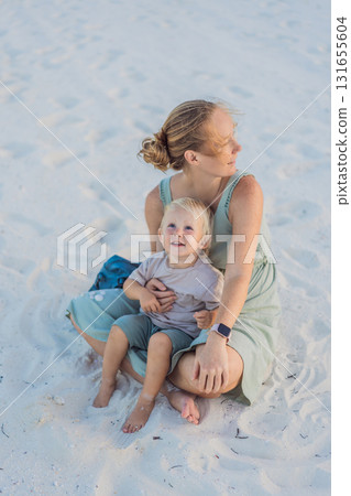 Mother and her little son sitting on a white sandy beach in Mexico during a peaceful evening, enjoying quality time together. Family bonding, summer relaxation, and vacation concept Mother and her little son sitting on a white sandy beach in Mexico during a peaceful evening, enjoying quality time together. Family bonding, summer relaxation, and vacation concept 131655604