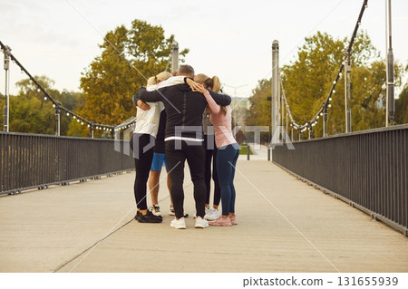 Group of friends hugging on a bridge during an outdoor fitness workout in the city Group of friends hugging on a bridge during an outdoor fitness workout in the city 131655939