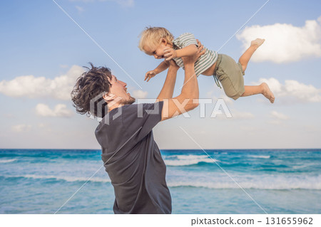 Father playfully lifts his young son in the air against the ocean background, creating a joyful family moment. Parenthood, love, bonding, summer vacation and carefree childhood concept Father playfully lifts his young son in the air against the ocean background, creating a joyful family moment. Parenthood, love, bonding, summer vacation and carefree childhood concept 131655962