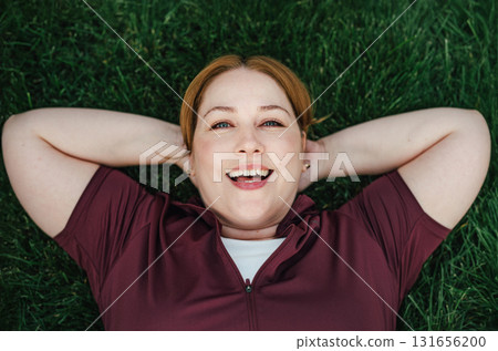 Beautiful plus size woman lying on grass after outdoors training session. Beautiful plus size woman lying on grass after outdoors training session. 131656200