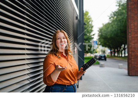Plus size woman holding tablet, black background. 131656210