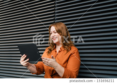 Plus size woman holding tablet, black background. 131656211