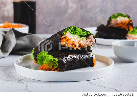 Tuna, cheese, Korean carrots and lettuce wrapped in nori on a plate on the table Tuna, cheese, Korean carrots and lettuce wrapped in nori on a plate on the table 131656331