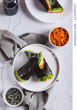 Rolls with tuna, Korean carrots, lettuce and sauce on a plate on the table top and vertical view 131656337