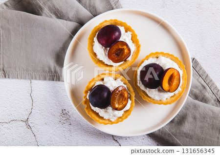 Close up of  mini tartlets with cottage cheese and plum on a plate on the table top view 131656345