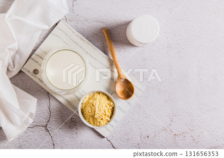 Colostrum powder in a bowl and a drink in a glass on a table top view 131656353