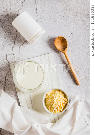 Bovine colostrum powder in a bowl and diluted drink in a glass on a table top and vertical view Bovine colostrum powder in a bowl and diluted drink in a glass on a table top and vertical view 131656355