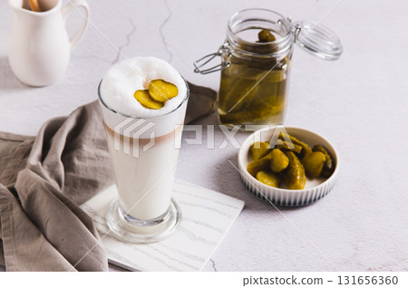 Picklatte with foam in a glass and pickles in a bowl on the table Picklatte with foam in a glass and pickles in a bowl on the table 131656360