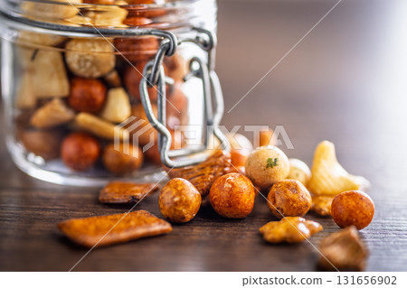 Salted snack. Coated peanuts and mini crackers on wooden table. 131656902