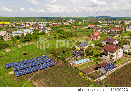 Aerial view of a private house in summer with blue solar photo voltaic panels on roof top and in the yard. 131656970
