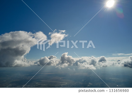 Aerial view from airplane window at high altitude of earth covered with white puffy cumulus clouds 131656980
