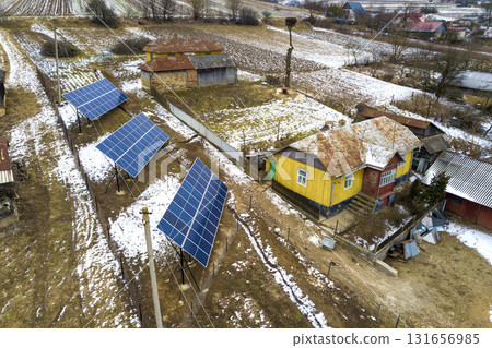 Aerial top view of stand-alone blue shiny solar photo voltaic panel systems producing renewable clean energy in rural residential area on sunny winter day. 131656985