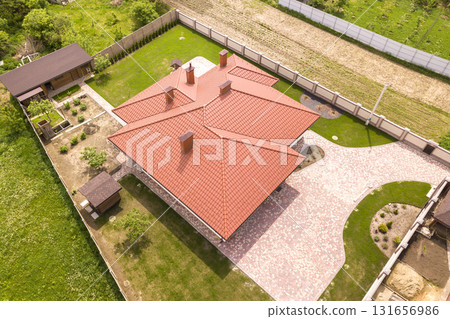 Aerial top view of new residential house cottage with shingle roof on fenced big yard on sunny day. 131656986