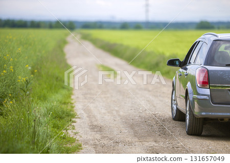 A car on dirt road in green field. 131657049
