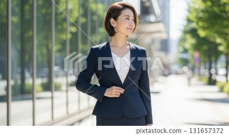 一位身穿西裝的女士凝視著遠方，背景則是一棟辦公大樓 131657372