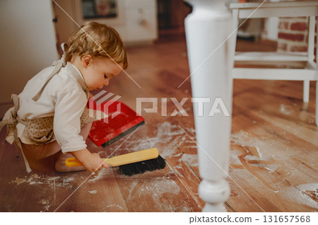 Little girl cleaning up flour mess in kitchen. Little girl cleaning up flour mess in kitchen. 131657568