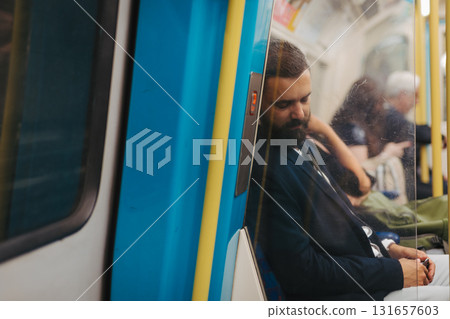 Side view of man napping in subway train, travelling from work. 131657603