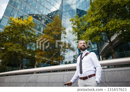 Man with suitcase walking down the street, heading to hotel to check in 131657621