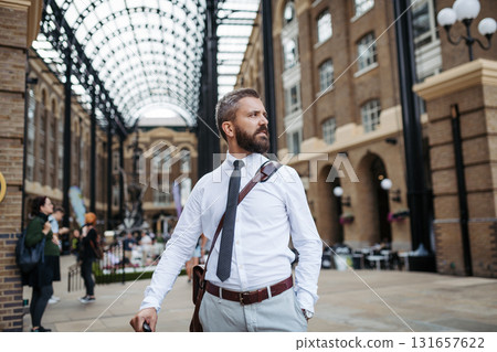 Man with suitcase walking down the street, heading to hotel to check in Man with suitcase walking down the street, heading to hotel to check in 131657622