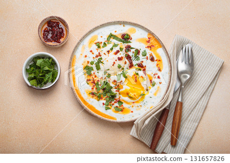 Turkish eggs cilbir, Middle Eastern style breakfast on beige background table top view 131657826