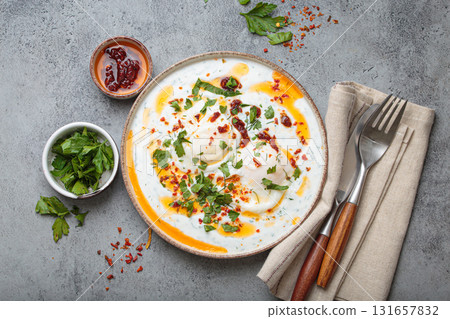 Turkish eggs cilbir, Middle Eastern style breakfast on grey concrete background table top view Turkish eggs cilbir, Middle Eastern style breakfast on grey concrete background table top view 131657832