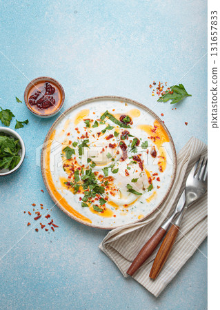 Turkish eggs cilbir, Middle Eastern style breakfast on blue background table top view Turkish eggs cilbir, Middle Eastern style breakfast on blue background table top view 131657833