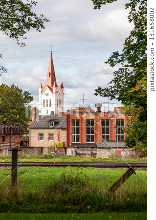 Historic church tower with red spire rising above old residential and industrial brick buildings  131658002