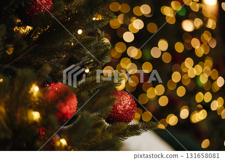 Red christmas baubles on fir tree branch with golden bokeh lights 131658081