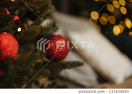 Red christmas baubles on fir tree branch with golden bokeh lights 131658083