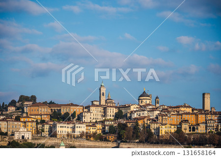 Panoramic view of Bergamo Alta in Italy with colorful historic buildings, church towers, and ancient walls under a bright blue sky Panoramic view of Bergamo Alta in Italy with colorful historic buildings, church towers, and ancient walls under a bright blue sky 131658164