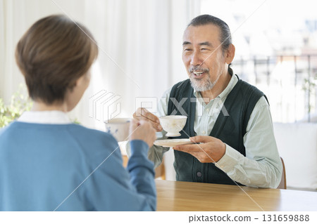 Senior men and women drinking tea facing each other 131659888