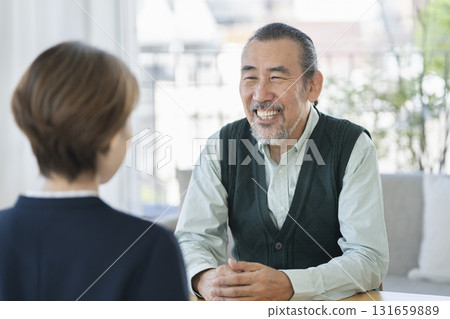 一位 70 多歲的男子與一位女商人面對面交談 131659889