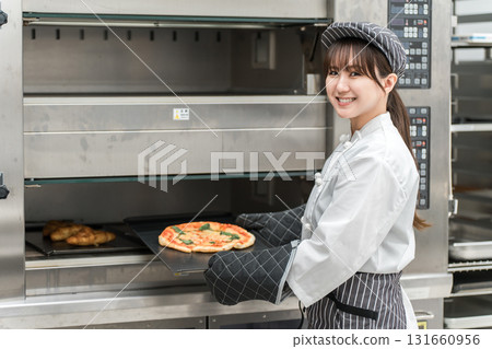 Female chef taking pizza out of the oven Female chef taking pizza out of the oven 131660956