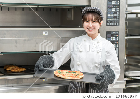 Female chef taking pizza out of the oven 131660957