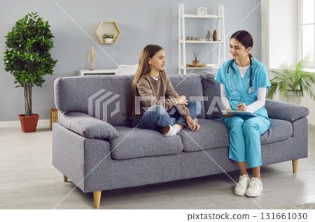 Child patient and woman pediatrician with clipboard sitting on couch and talking Child patient and woman pediatrician with clipboard sitting on couch and talking 131661030