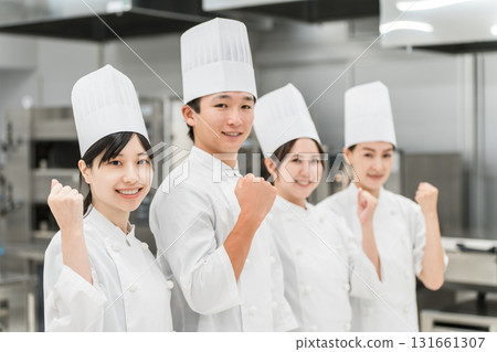 Chefs and cooks in chef coats standing in the kitchen (fist pump, motivated) Chefs and cooks in chef coats standing in the kitchen (fist pump, motivated) 131661307
