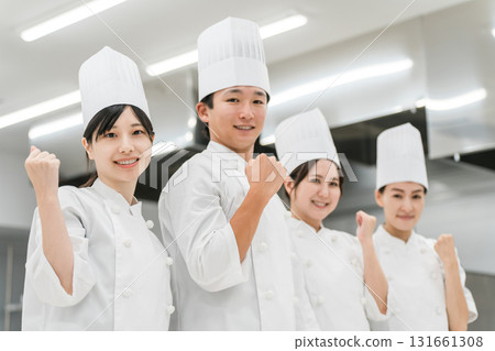 Chefs and cooks in chef coats standing in the kitchen (fist pump, motivated) Chefs and cooks in chef coats standing in the kitchen (fist pump, motivated) 131661308