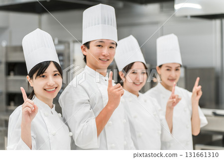 Chefs and cooks in chef coats standing in the kitchen (pointing, pointing, guiding, introducing) 131661310