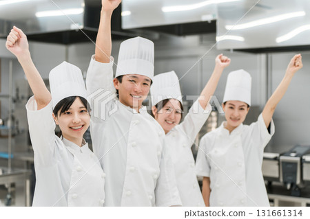 Chefs and cooks in chef coats standing in the kitchen (fist pump) 131661314