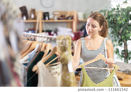 Young woman choosing t-shirt in clothing store Young woman choosing t-shirt in clothing store 131661542
