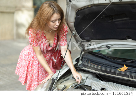 Woman looking under the hood of the car 131661554