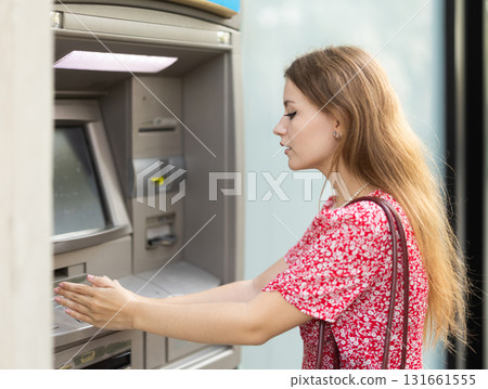 Woman uses ATM, withdraws cash from card. Girl buys travel ticket from machine Woman uses ATM, withdraws cash from card. Girl buys travel ticket from machine 131661555