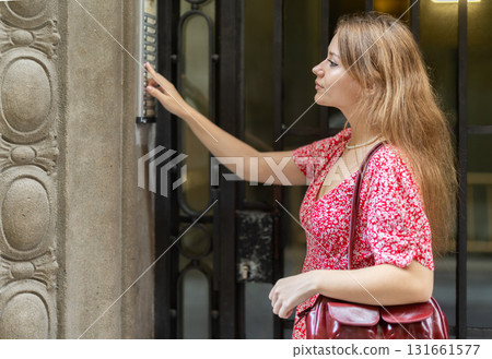 Young woman standing near intercom Young woman standing near intercom 131661577