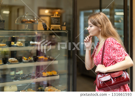 Girl choosing sweet cookies or cupcakes at street bakery display Girl choosing sweet cookies or cupcakes at street bakery display 131661593