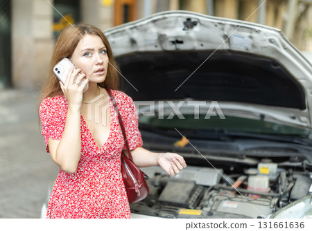 woman stands near a broken car with a phone in her hands woman stands near a broken car with a phone in her hands 131661636